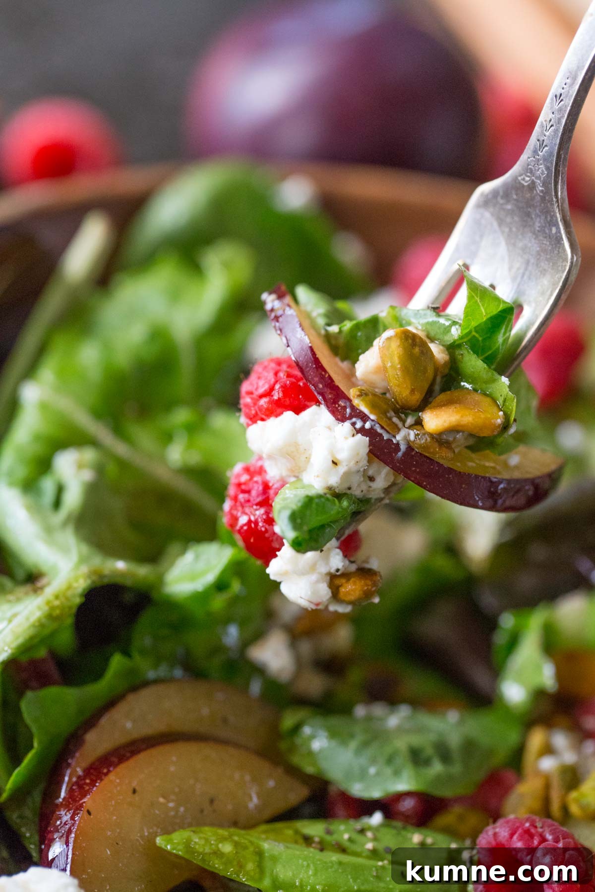 Summer Fruit Salad with Goat Cheese & Pistachios for Entertaining 6 A fork full of Summer Fruited Salad with Goat Cheese and Pistachios held over the bowl of salad.