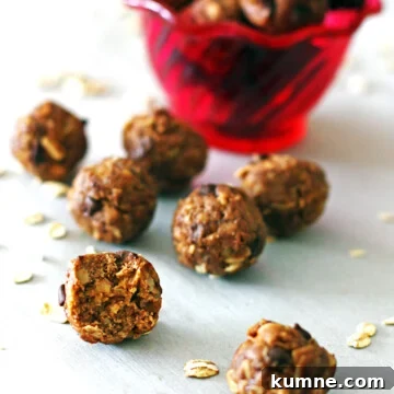 Peanut butter energy balls in front of a red bowl with a bite taken out of one of them.