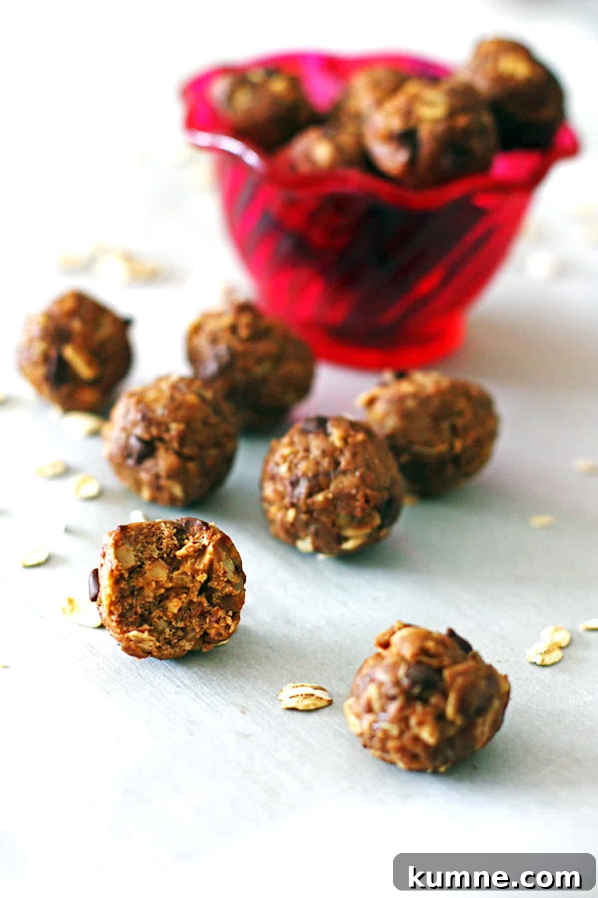 No-Bake Peanut Butter Energy Balls Recipe for Quick Snacks 4 Peanut butter energy balls in front of a red bowl with a bite taken out of one of them.