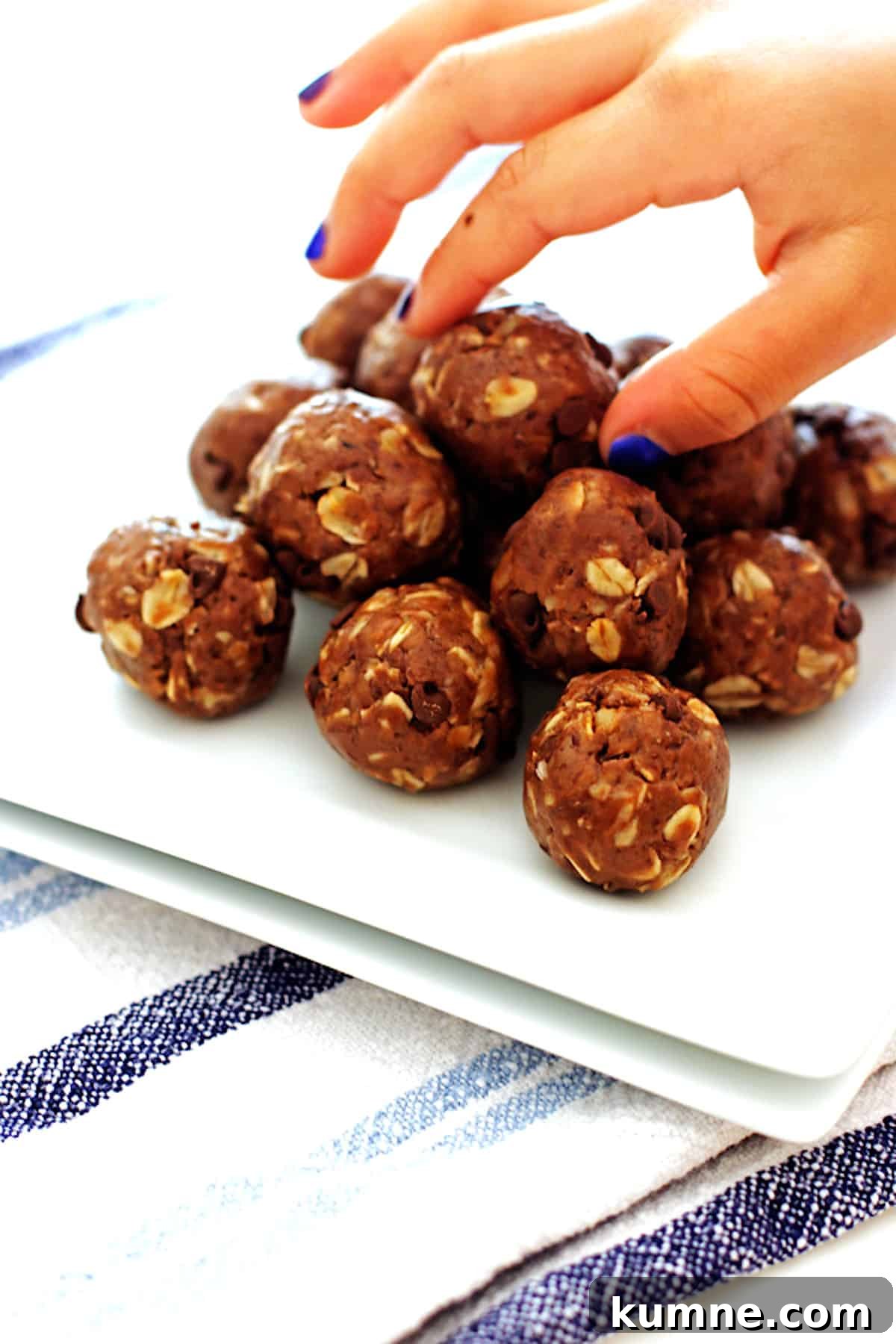 No-Bake Peanut Butter Energy Balls Recipe for Quick Snacks 5 Peanut butter protein bites on a white plate being picked up by a hand.