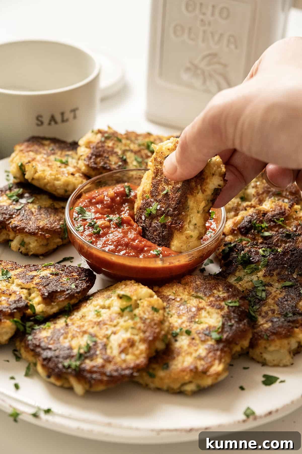 Fried cauliflower cakes on a plate with marinara sauce. 