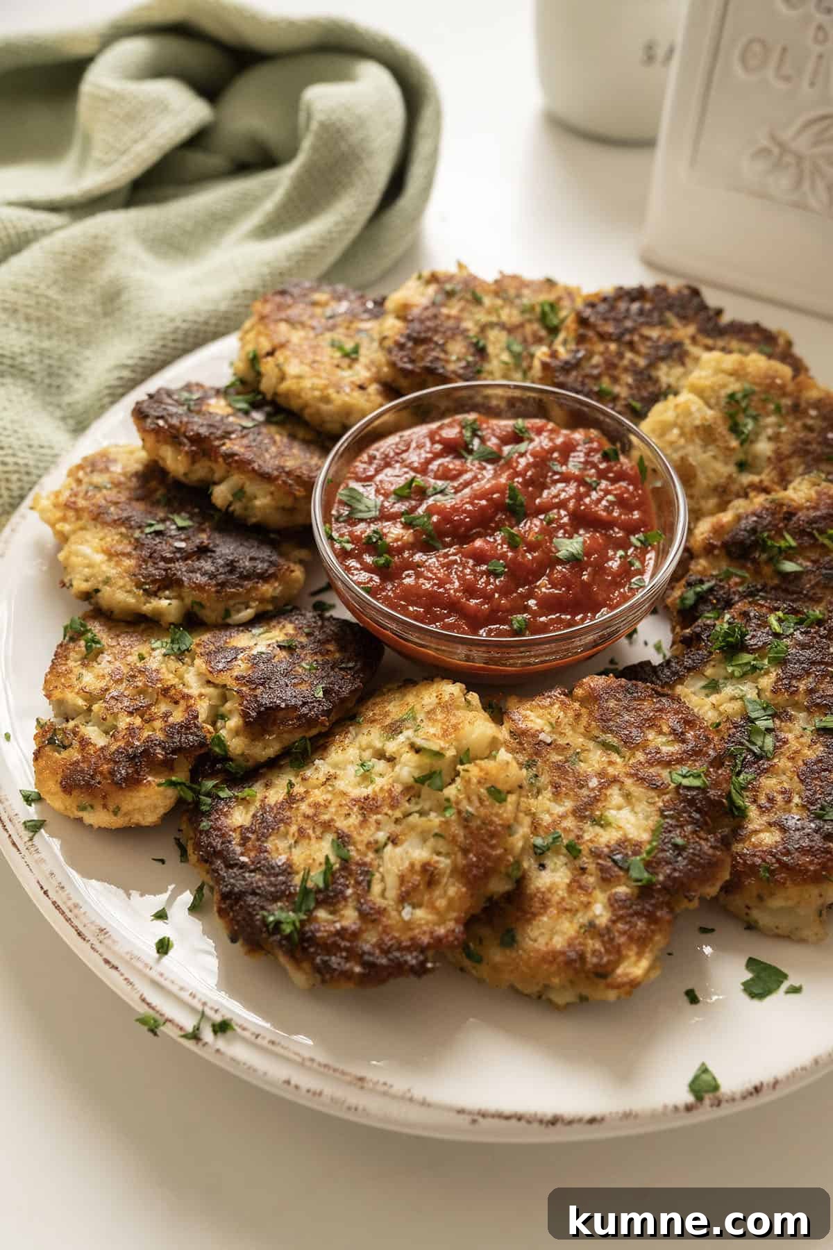 Fried cauliflower cakes on a plate with marinara sauce.