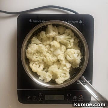 Cauliflower in steamer basket in a pot.
