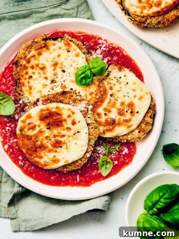 Vegetarian air fryer eggplant parmesan with marinara sauce on a dinner plate.