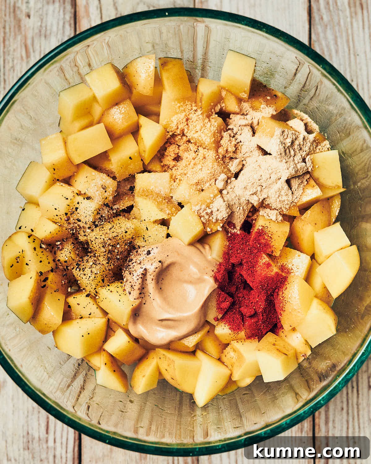 Diced potatoes in a bowl with other ingredients to make breakfast potatoes, about to be mixed.