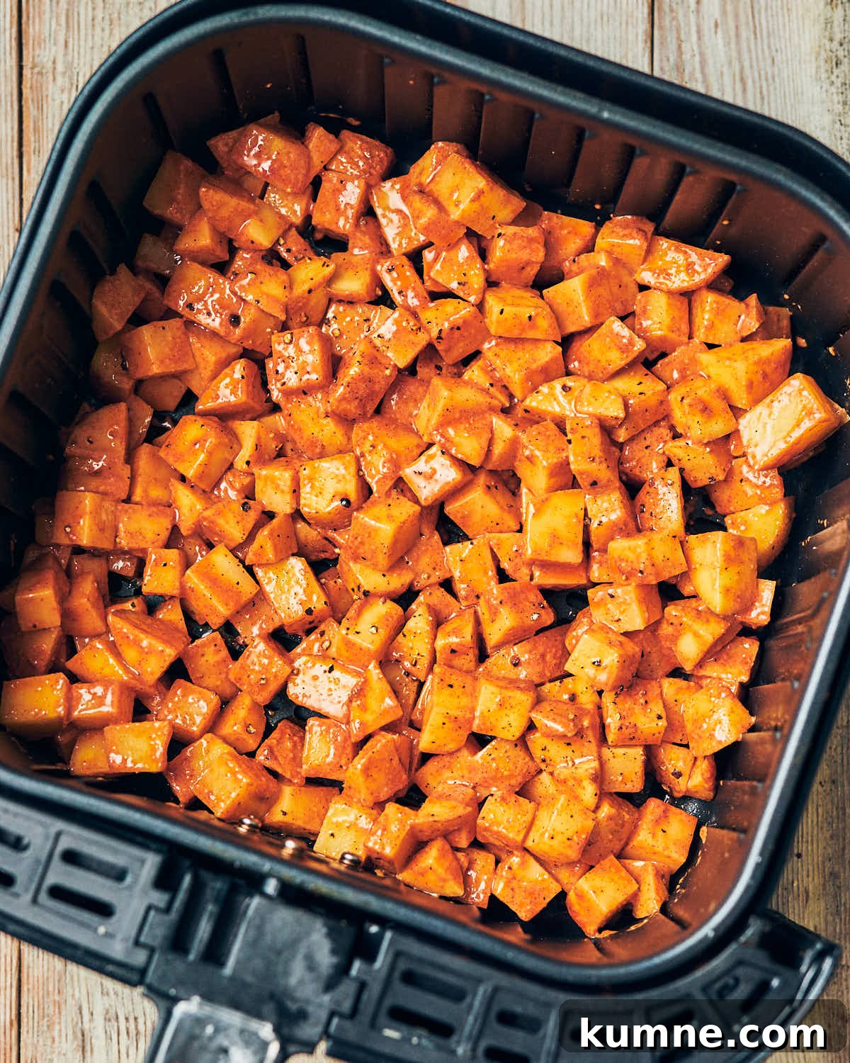 Seasoned breakfast potatoes in an air fryer basket about to be baked.