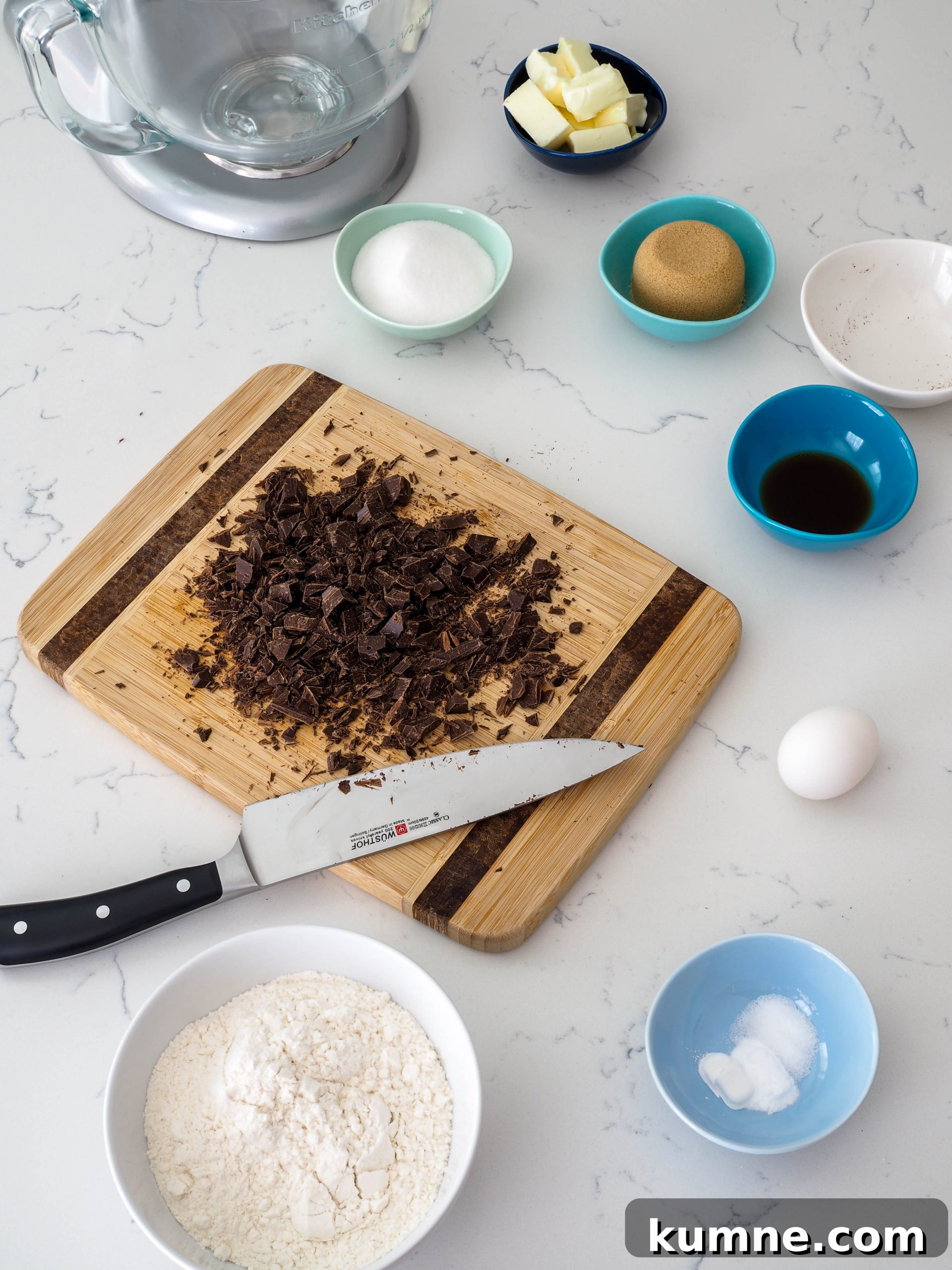 Decadent Dark Chocolate Chunk Cookie Recipe 4 A cutting board covered with roughly chopped chocolate and a Wusthof chef's knife is surrounded by cookie ingredients.