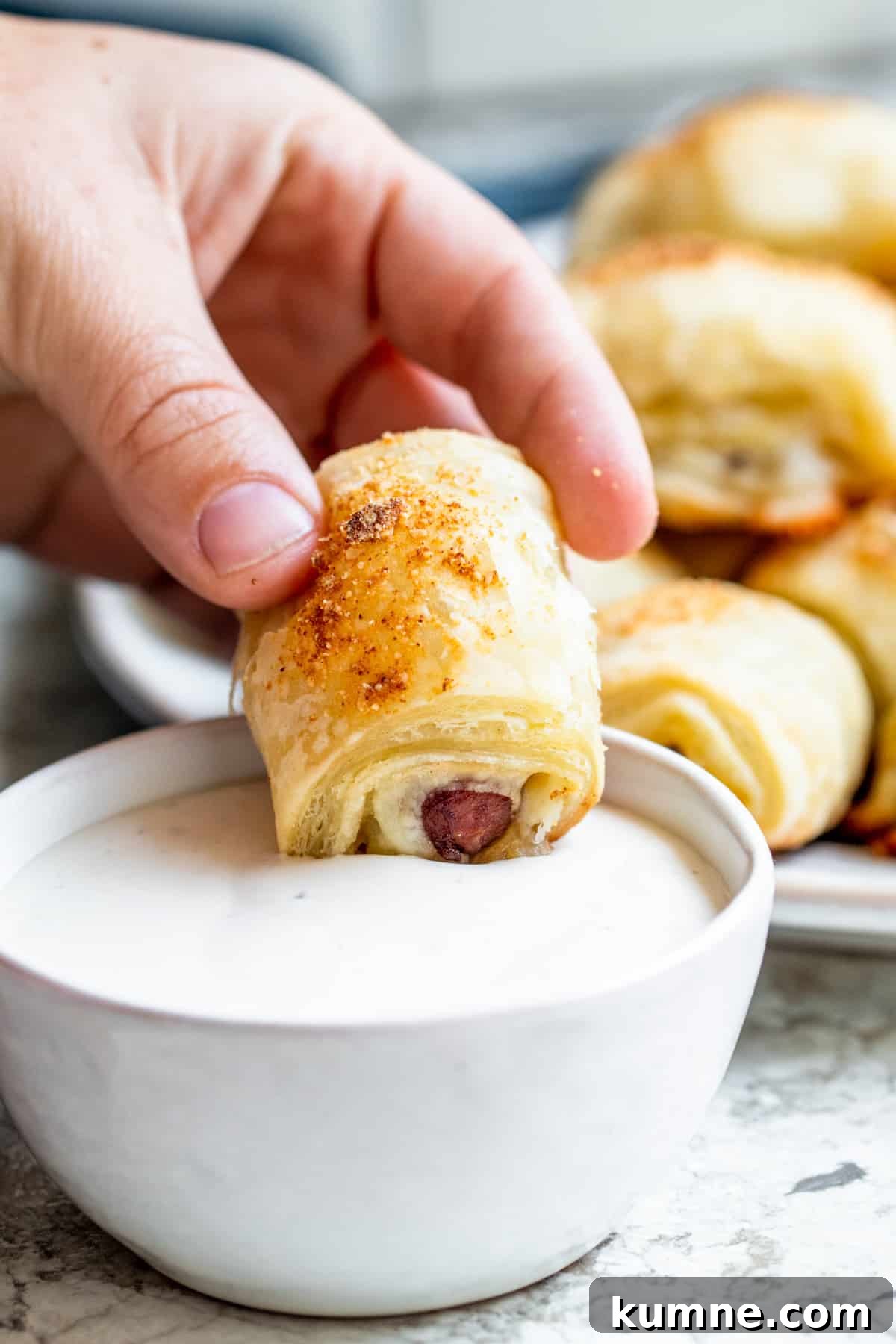 Cheesy Puff Pastry Pigs in a Blanket Recipe 5 Hand dipping mini crescent dog into ranch dressing.