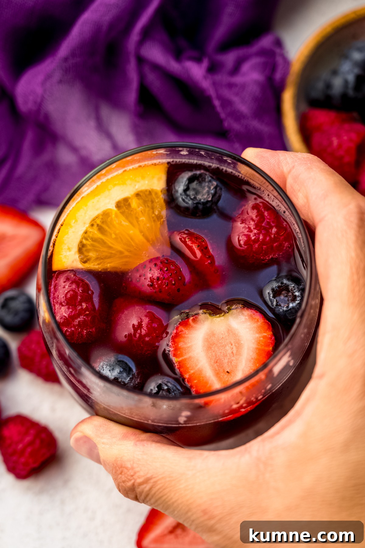 Berry Sangria and Refreshing Non-Alcoholic Berry Mocktail 2 Aerial photo of someone's hand around a glass of berry sangria.