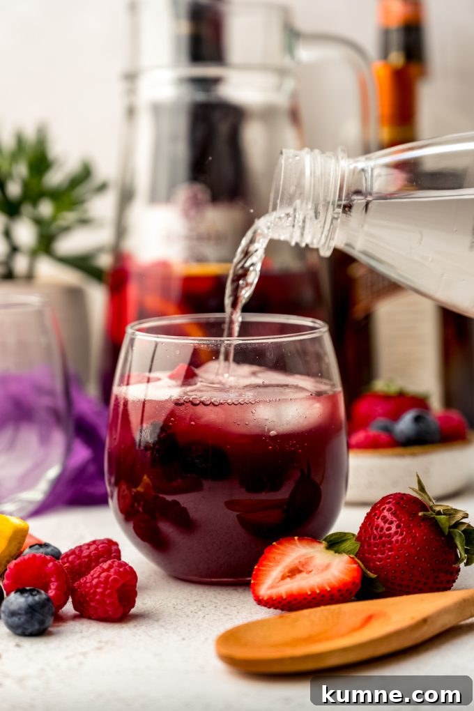 Berry Sangria and Refreshing Non-Alcoholic Berry Mocktail 14 Someone is pouring seltzer water into a glass of berry sangria.