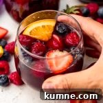 Berry Sangria and Refreshing Non-Alcoholic Berry Mocktail 19 Someone's hand around a glass of berry sangria.