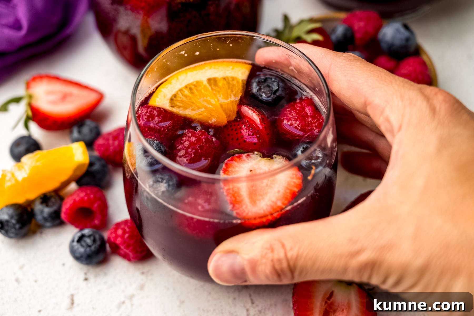 Berry Sangria and Refreshing Non-Alcoholic Berry Mocktail 5 Someone's hand around a glass of berry sangria.