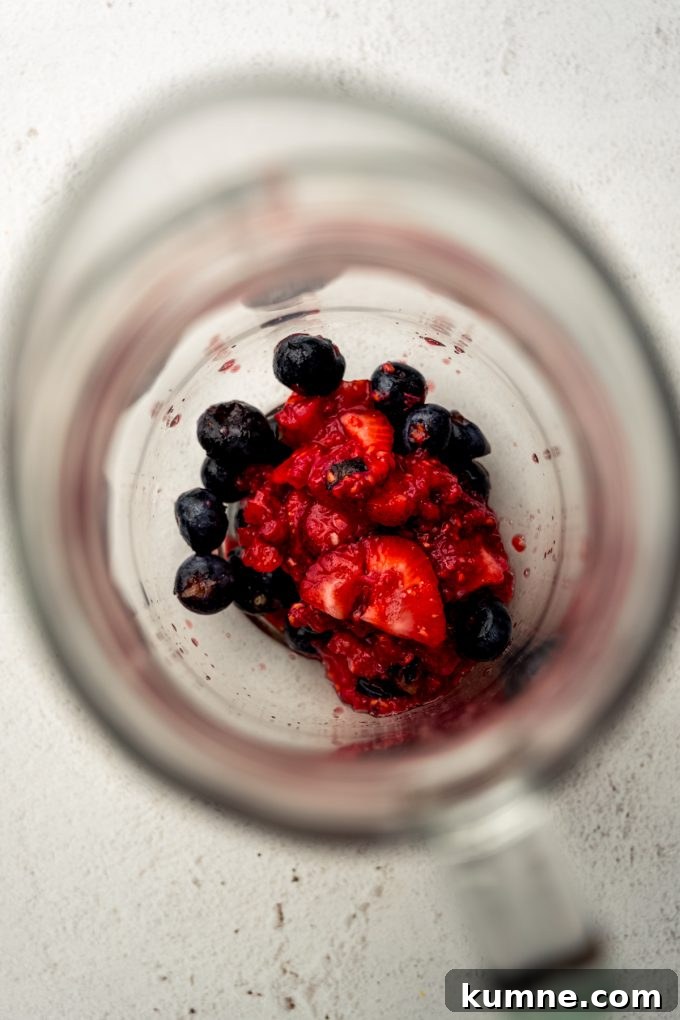 Berry Sangria and Refreshing Non-Alcoholic Berry Mocktail 8 Macerated blueberries, strawberries, and raspberries in the bottom of a glass pitcher.