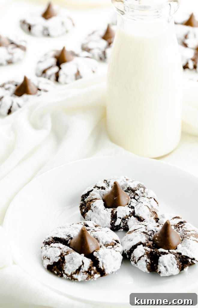 Chocolate crinkle kiss cookies on a plate with a glass of milk.