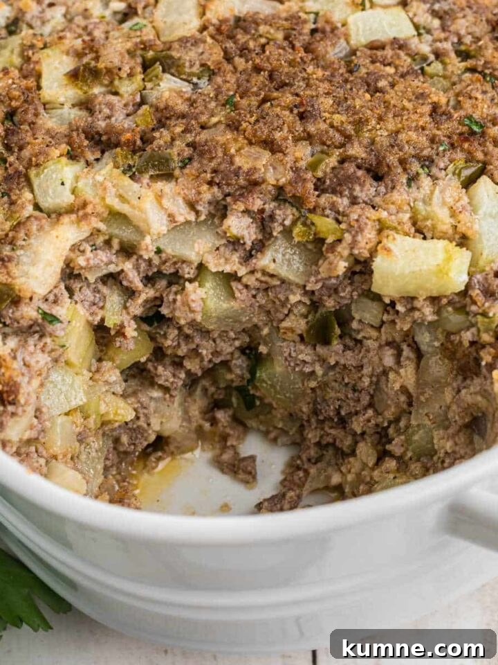 Close up of a dish full of mirliton dressing, with a scoop missing.