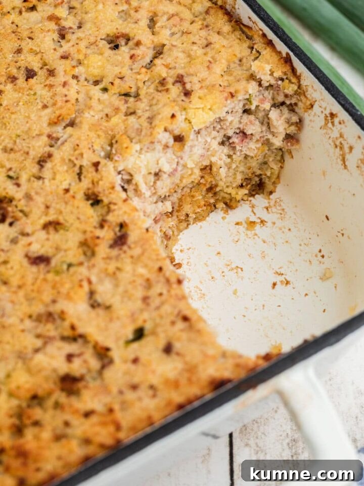 A corner of a dish with Cajun cornbread dressing made in it, with a corner scooped out.