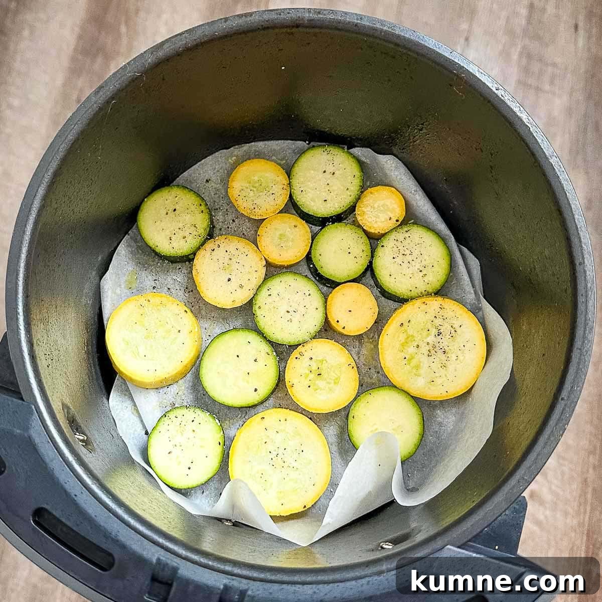 Zucchini and squash coated in olive oil, salt, and pepper in the air fryer basket.