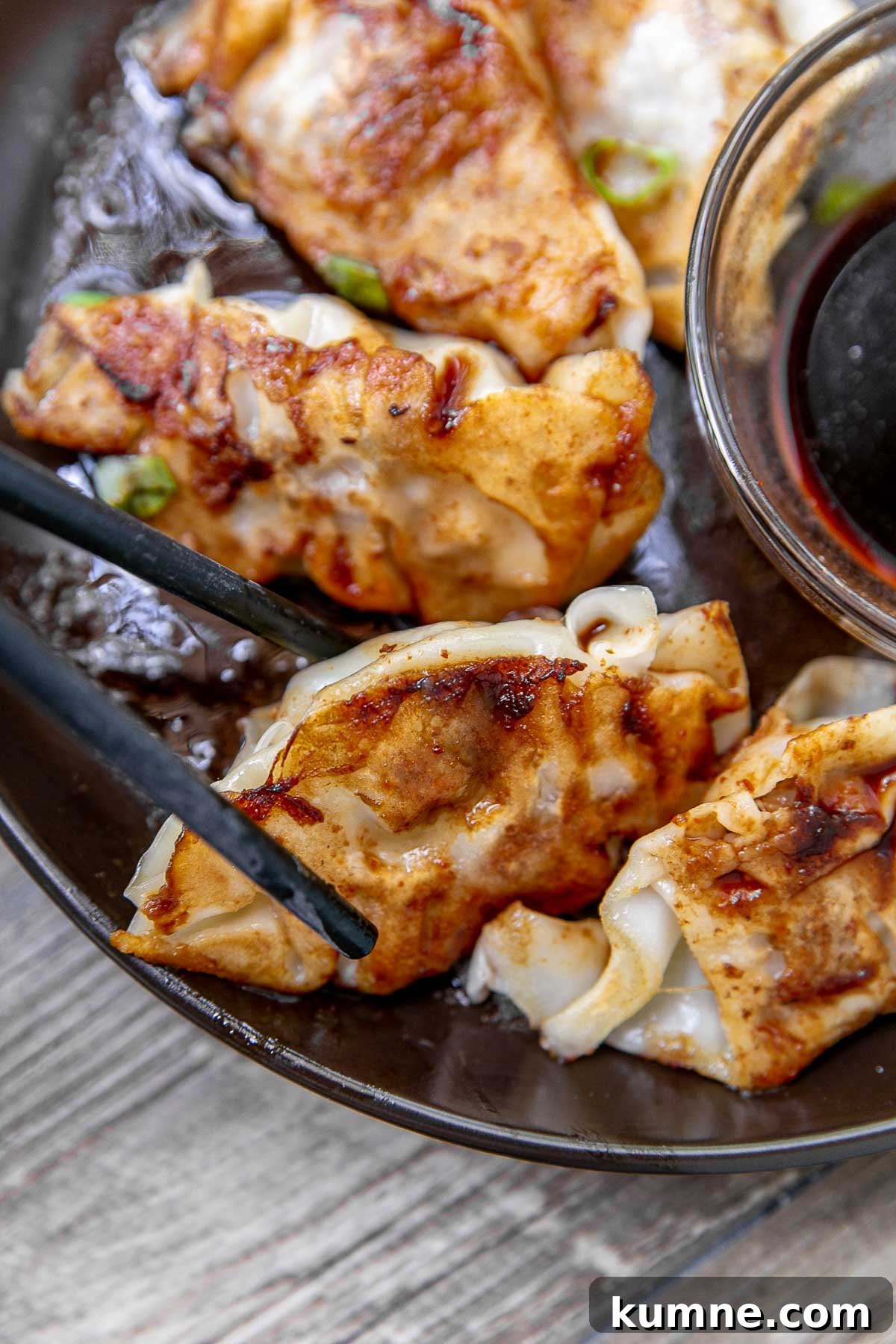 Crispy Pork Potstickers with Ginger Soy Dipping Sauce 2 Pork potstickers with dipping sauce on a serving platter.