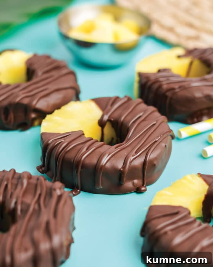 Chocolate covered pineapple on a tabletop with yellow and white straws.