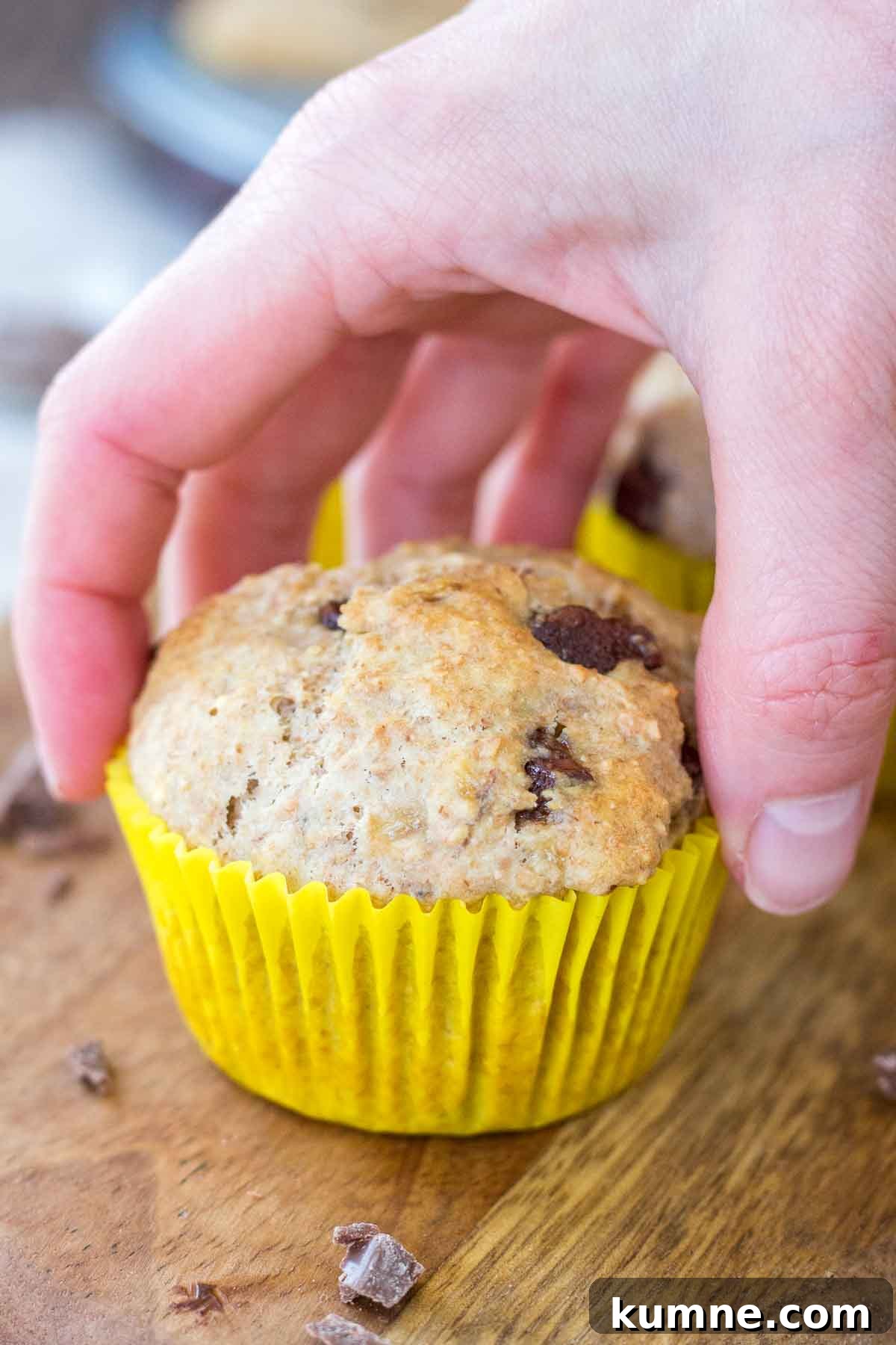 Hand taking a banana chocolate chip muffin.
