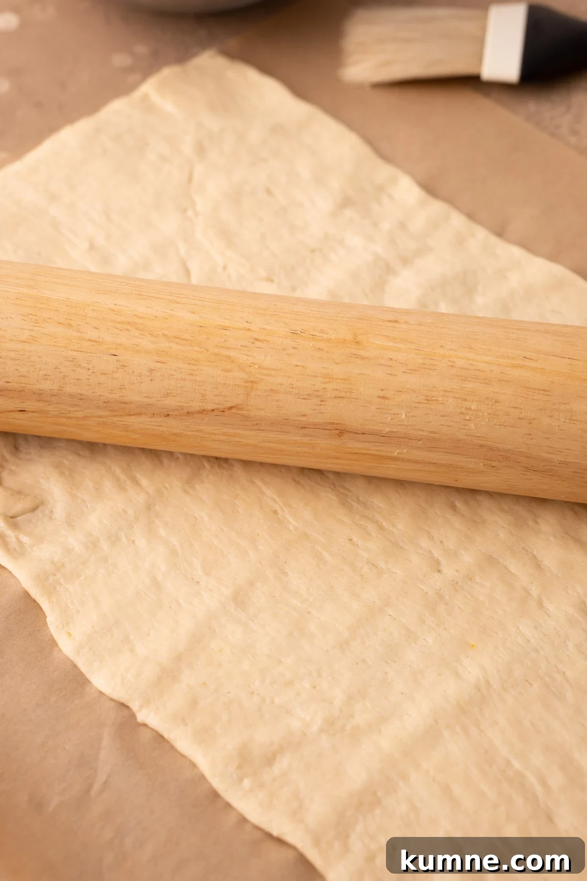 Crescent Roll Sheets being rolled out on a piece of parchment paper.