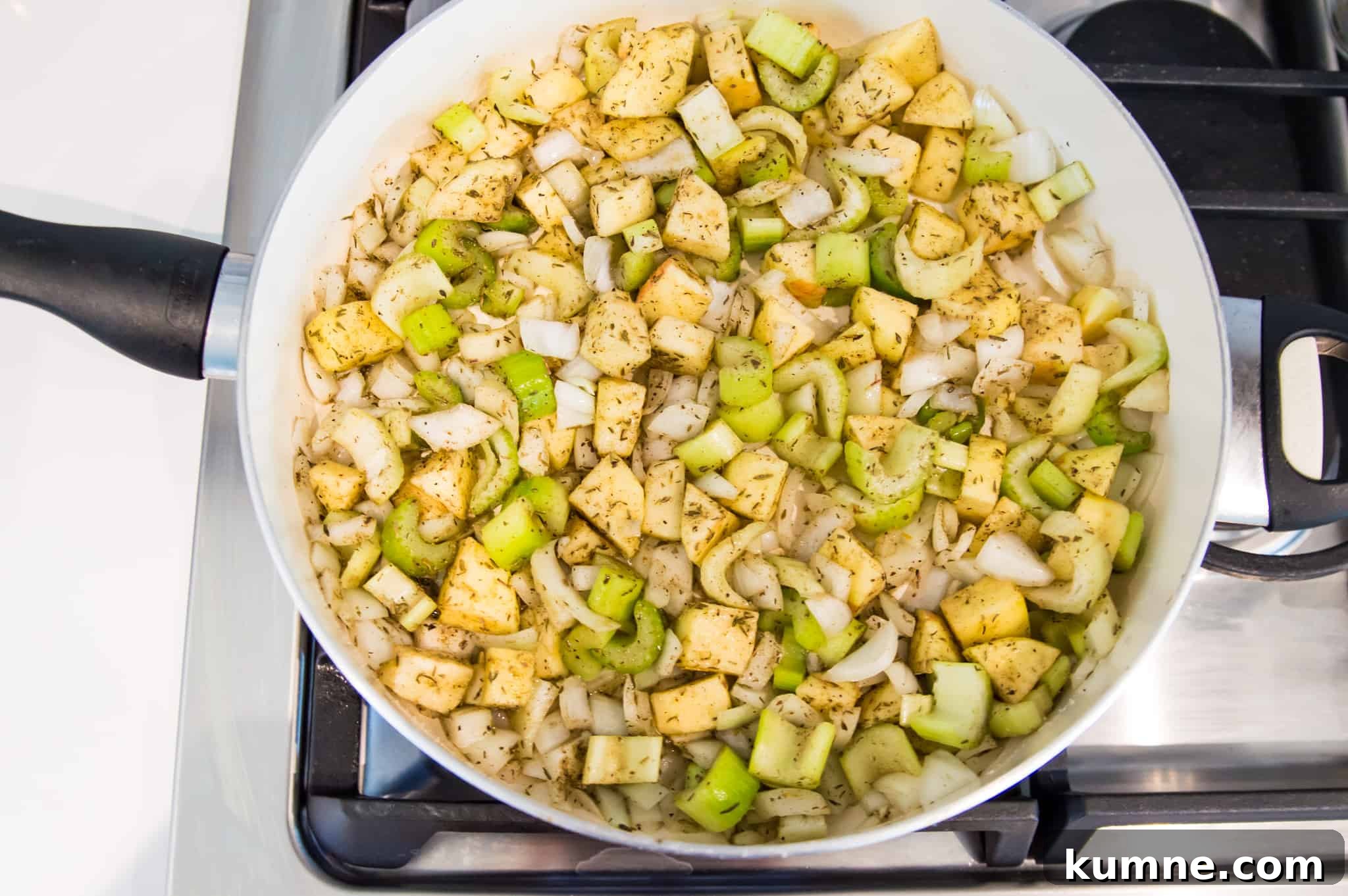 Gluten-Free Paleo Stuffing Made with Paleo Bread 4 A pan on the stovetop with chopped onion, celery and apple cooking in it.
