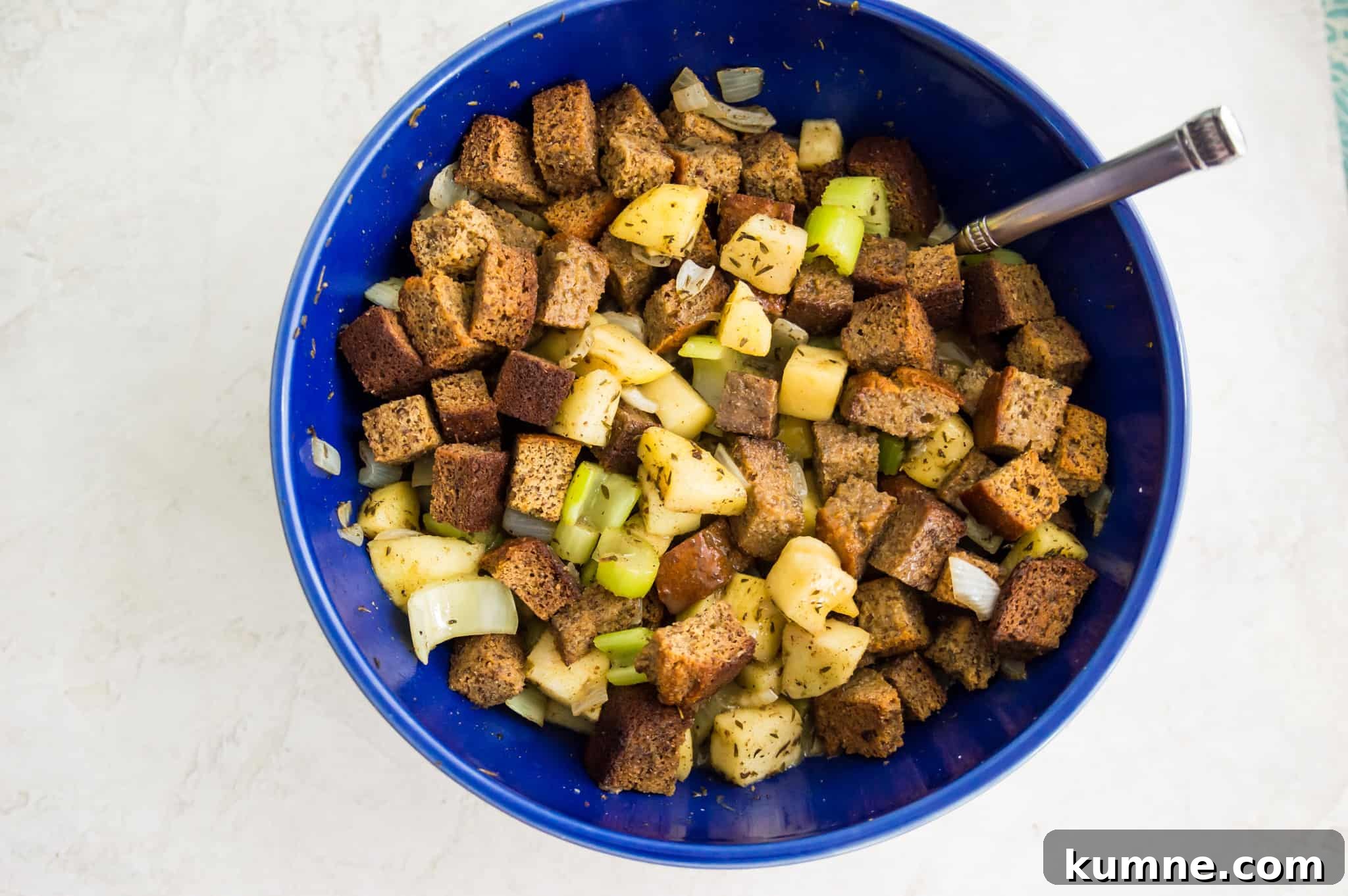 Gluten-Free Paleo Stuffing Made with Paleo Bread 7 A bowl with uncooked bread cubes, chopped onion, celery and apples in it.