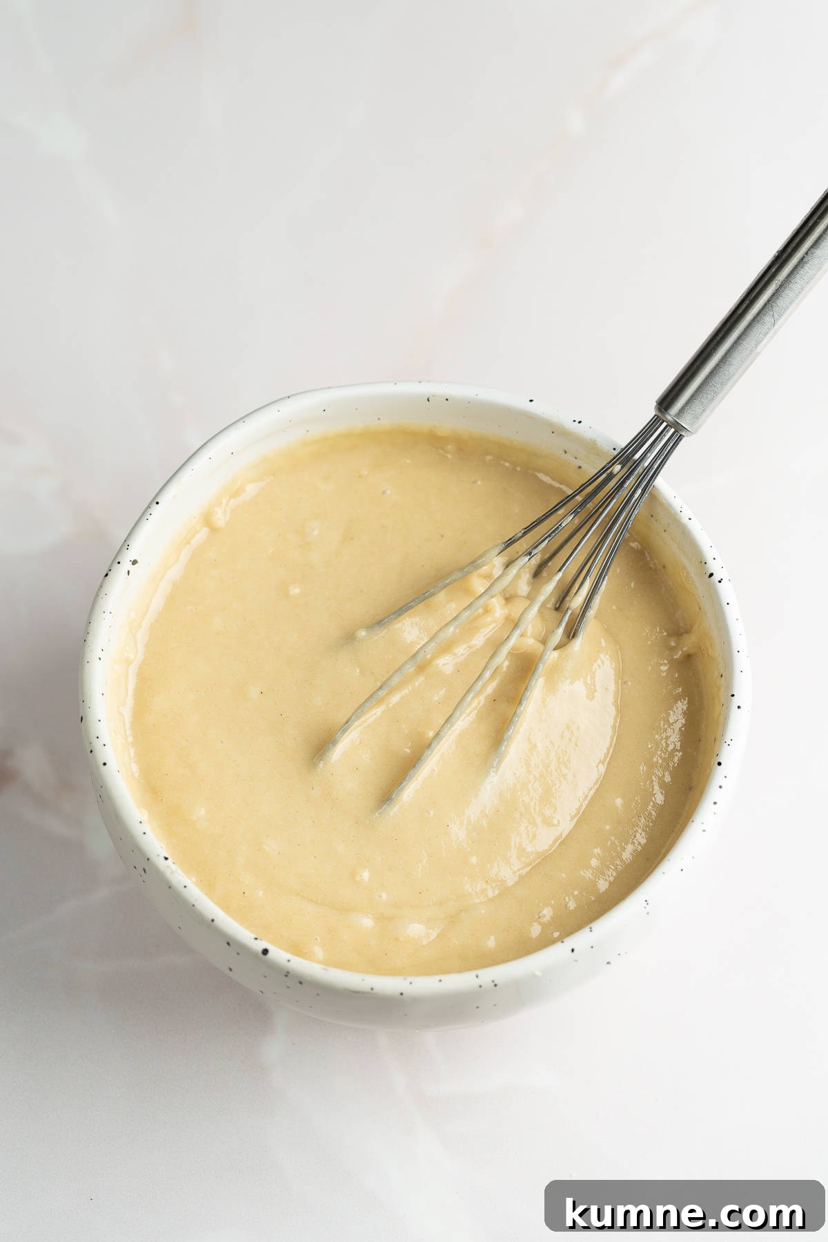 Bread batter in a bowl with a hand whisk .