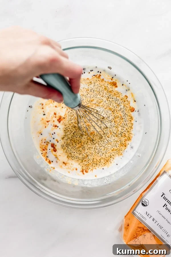 Turmeric Golden Milk Chia Pudding Recipe 6 a hand whisking a bowl of chia seeds, coconut milk and turmeric