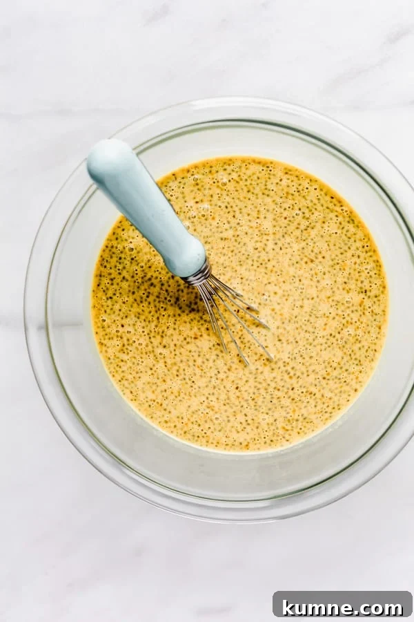 Turmeric Golden Milk Chia Pudding Recipe 7 a clear mixing bowl with a chia pudding and a whisk in it