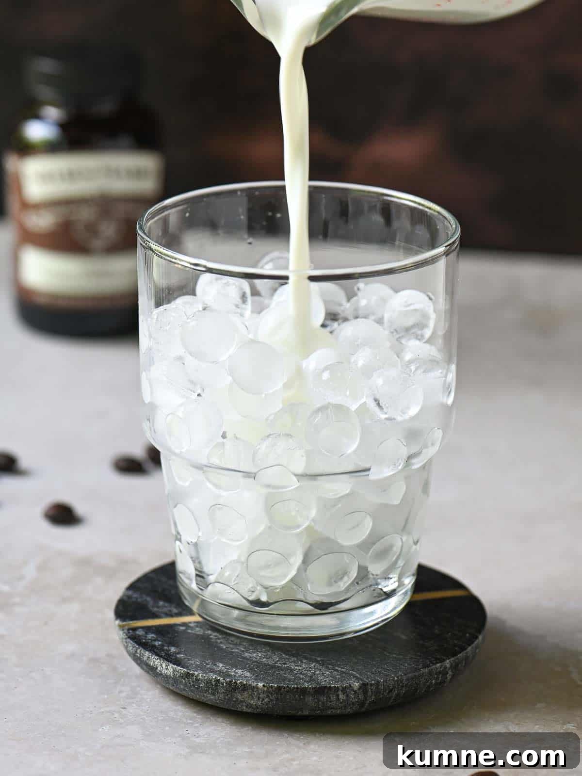 Iced Vanilla Bean Latte Recipe Using Real Vanilla Extract 5 Milk being poured into a clear glass with ice.