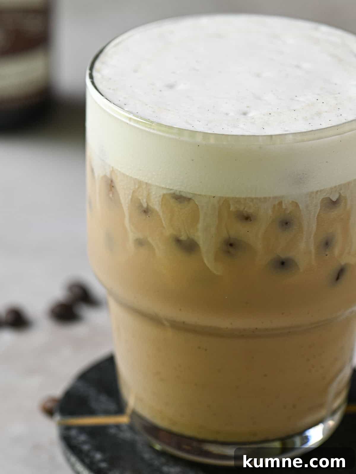 Iced Vanilla Bean Latte Recipe Using Real Vanilla Extract 8 Close-up of milk and coffee mixed in a clear cup showing milk streaks.