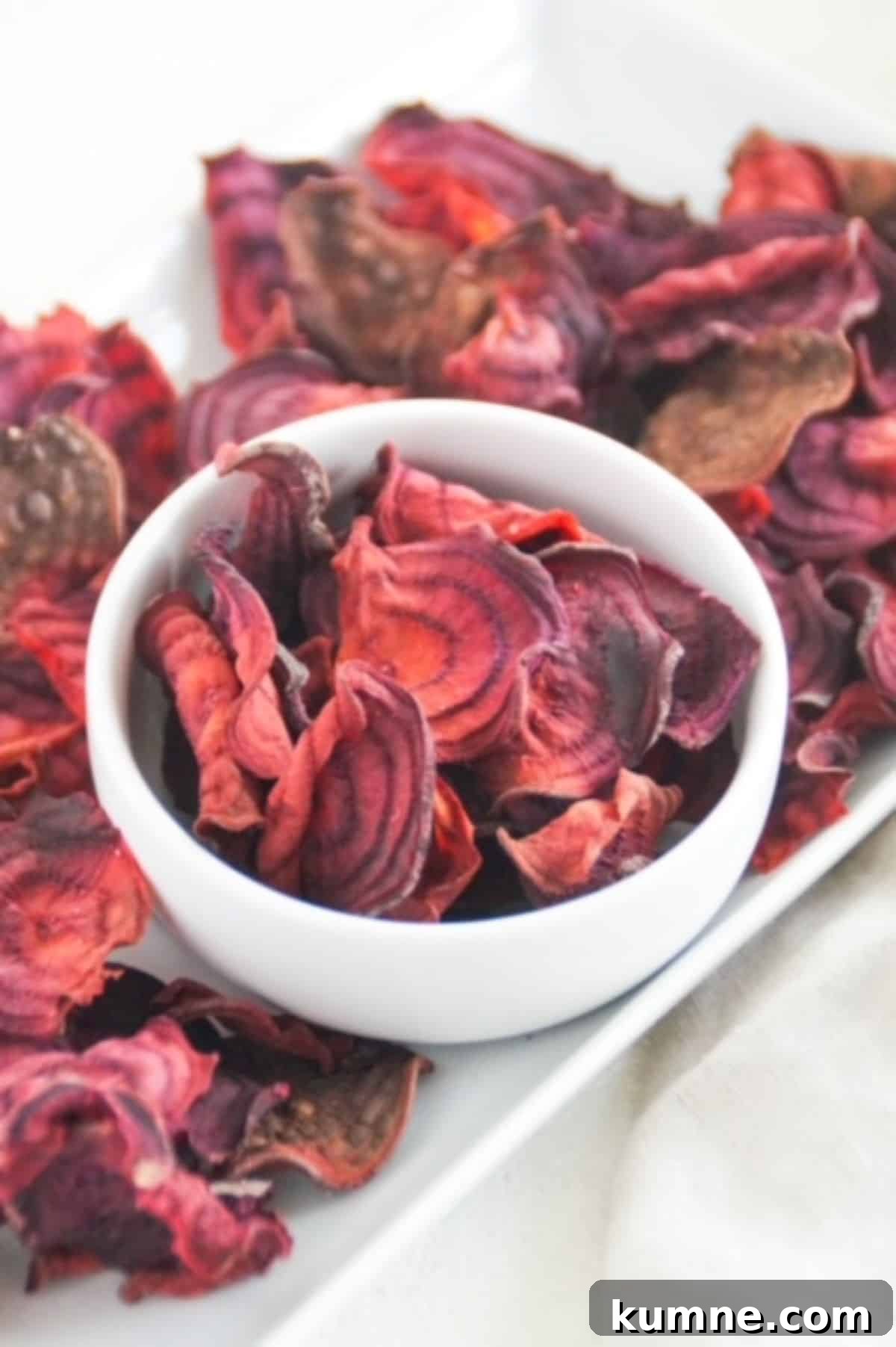 Beet chips in a white bowl and white serving dish.