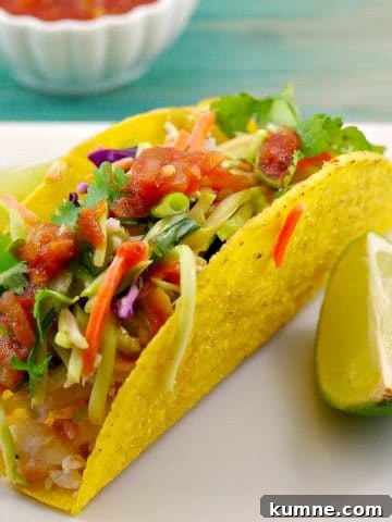healthy fish taco on a white plate with a wedge of lemon