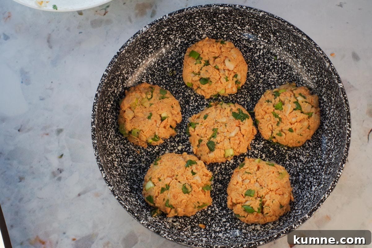 6 salmon patties in frying pan (uncooked).