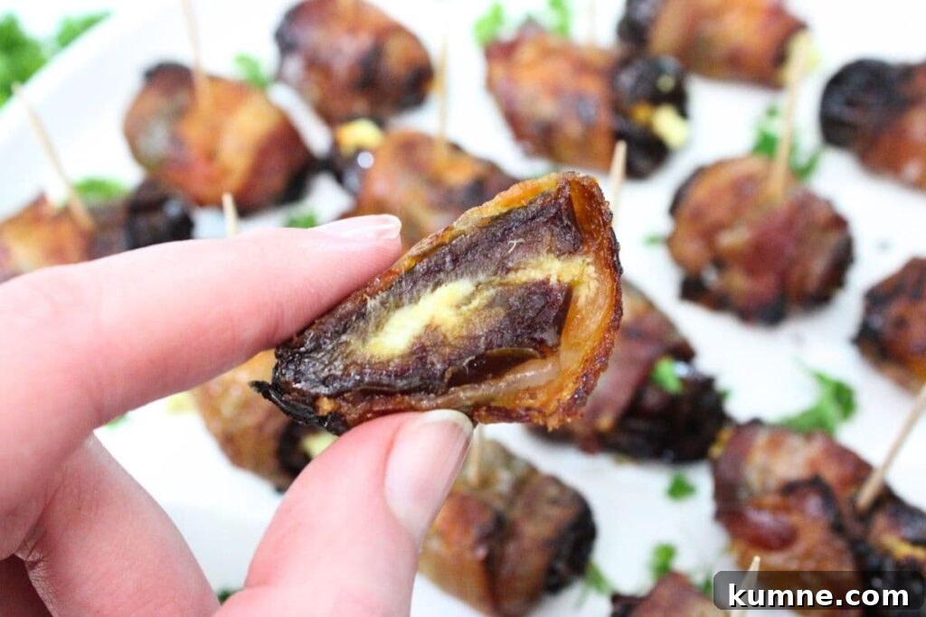 Crispy Air Fryer Bacon-Wrapped Dates Stuffed with Goat Cheese 3 holding up a cut in half air fryer bacon wrapped date stuffed with goat cheese