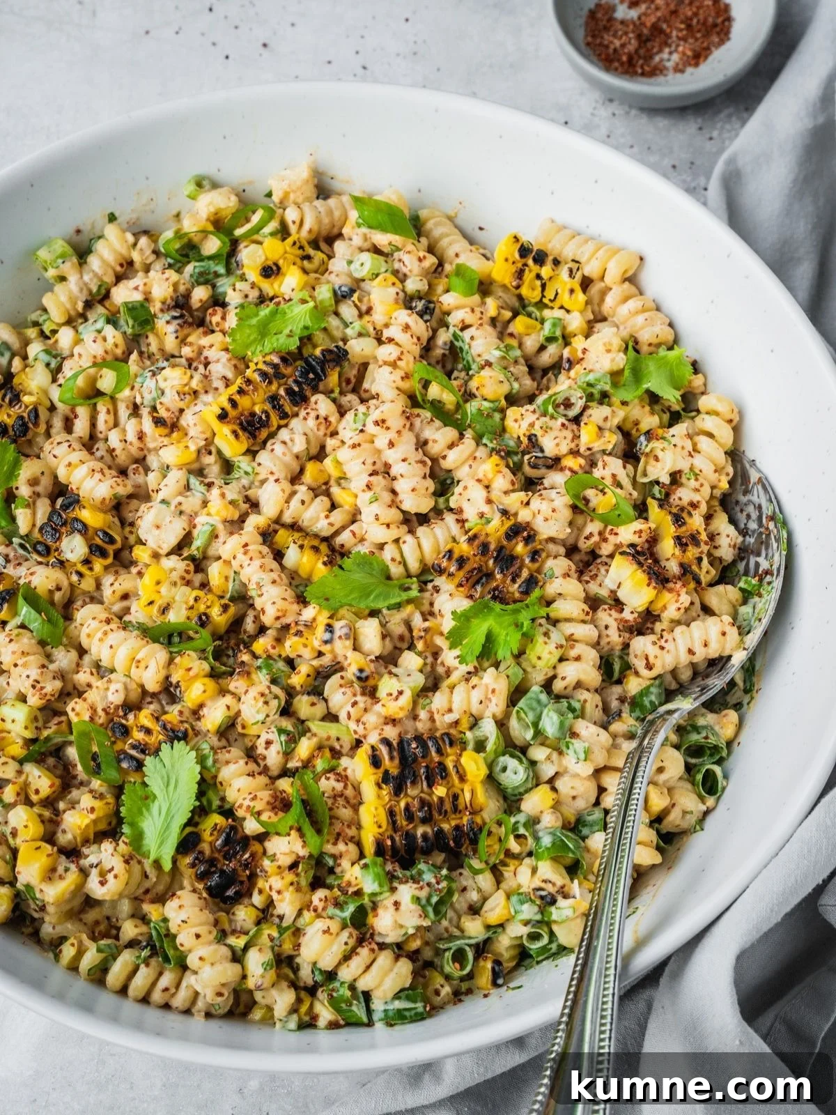 Elote Pasta Salad Inspired by Mexican Street Corn 2 Mexican-inspired elote pasta salad in a large bowl garnished with tajin, fresh cilantro and chopped green onion.