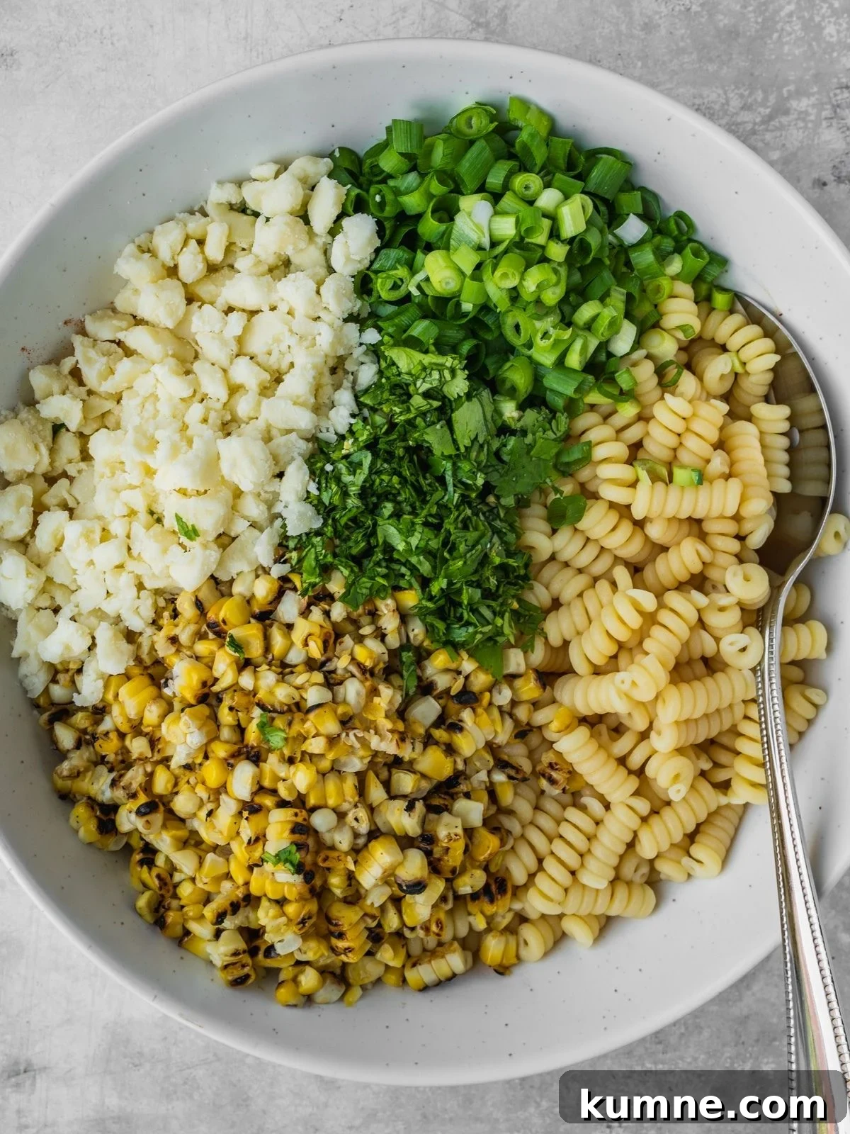 Elote Pasta Salad Inspired by Mexican Street Corn 7 Cooked pasta, corn kernels, chopped green onion, chopped cilantro and crumbled cotija cheese in the serving bowl.