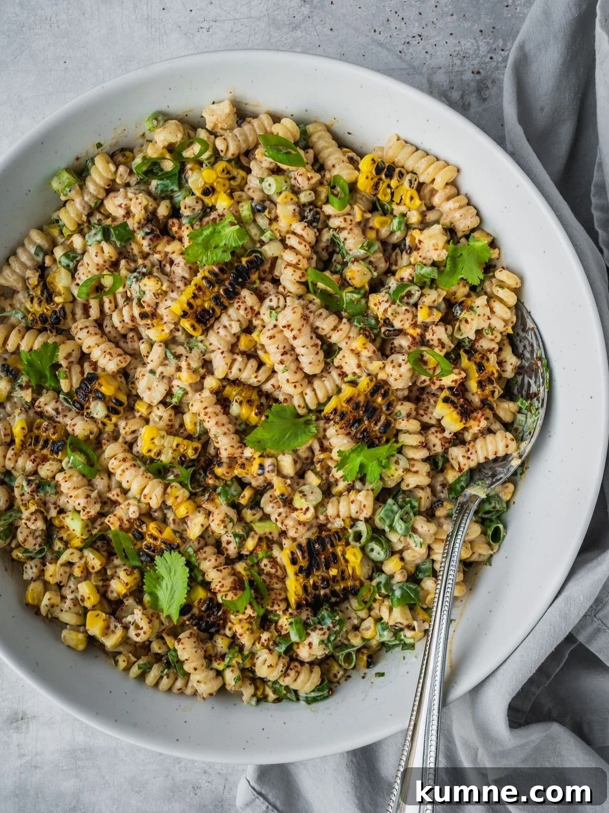 Elote Pasta Salad Inspired by Mexican Street Corn 8 Mexican-inspired elote pasta salad in a large bowl garnished with tajin, fresh cilantro and chopped green onion.