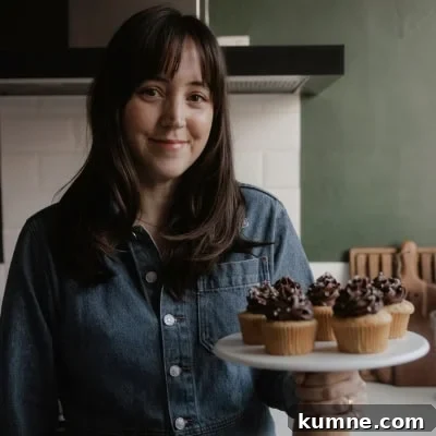 Moist Chocolate Cupcakes with Cream Cheese Frosting Recipe 16 Ella from Alpine Ella is holding a cake stand with cupcakes on it.