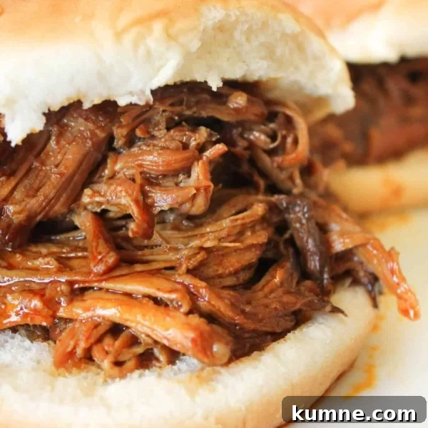 10 Make-Ahead Slow Cooker Freezer Meals You Can Prep in 90 Minutes 11 A close-up of a sandwich with shredded barbecue meat filling on a white bun, with another similar sandwich in the background.