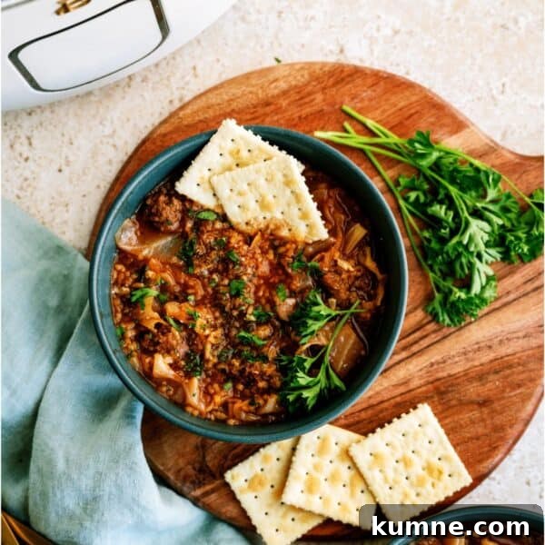 10 Make-Ahead Slow Cooker Freezer Meals You Can Prep in 90 Minutes 6 A bowl of cabbage roll soup garnished with parsley and served with saltine crackers, on a wooden board with fresh parsley and a slow cooker in the background.