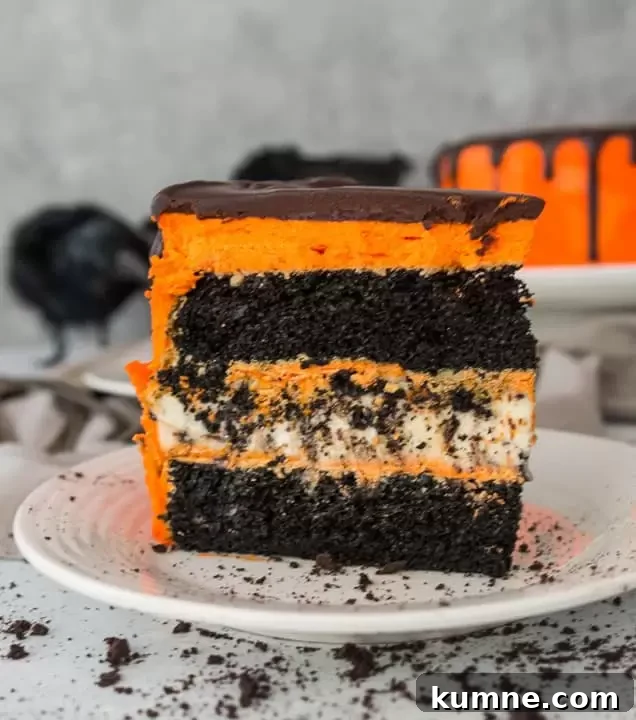 slice of black velvet cookies and cream cheesecake cake on a plate with crushed Oreos scattered around it