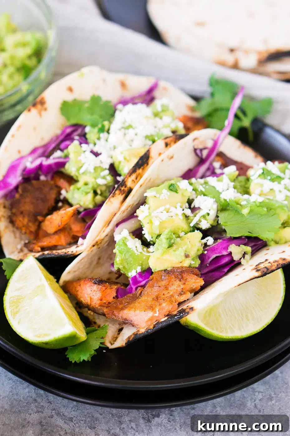 Citrus-Glazed Salmon Tacos with Avocado Slaw 7 fish tacos with salmon, avocados, cabbage on a plate