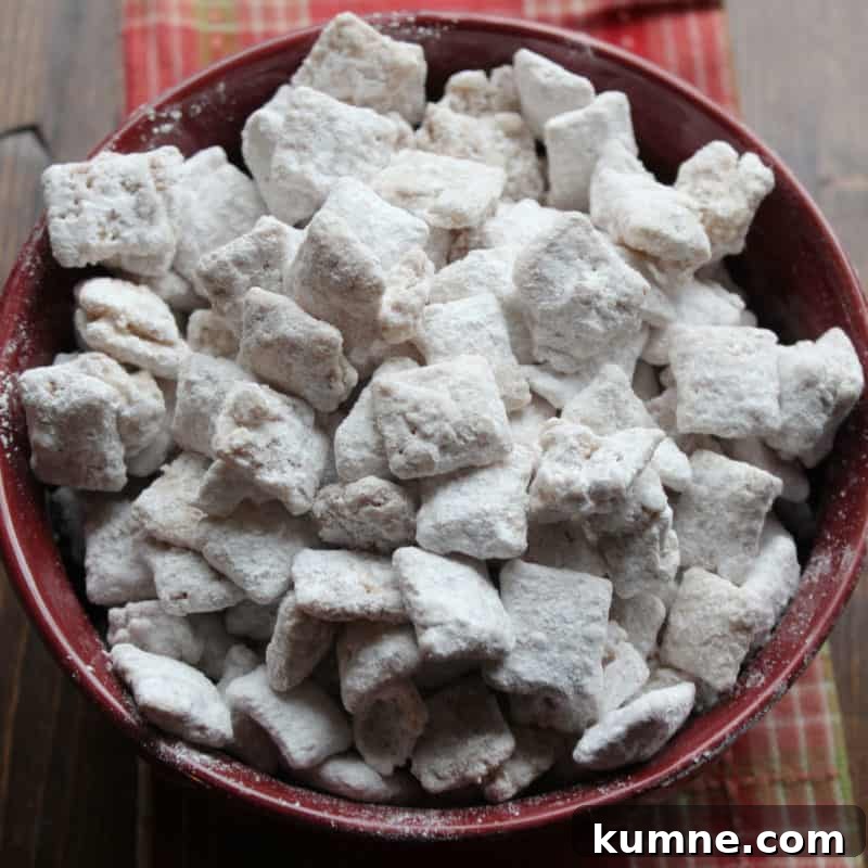 Top Fall Dessert Recipes You Need to Try This Season 24 Apple Cider Muddy Buddies in a burgundy bowl on a wood board