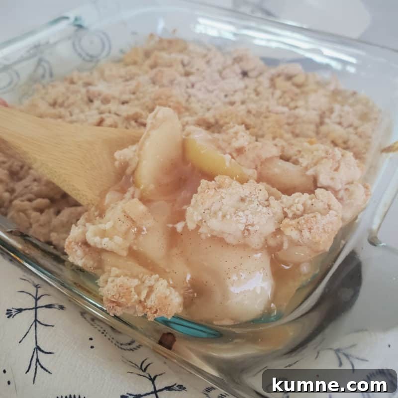 Top Fall Dessert Recipes You Need to Try This Season 7 Bisquick Apple Cobbler in a glass baking dish with a wooden spoon scooping out some cobbler
