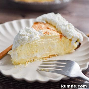 A slice of the no-bake eggnog pie is on a plate with a fork and a cinnamon stick.