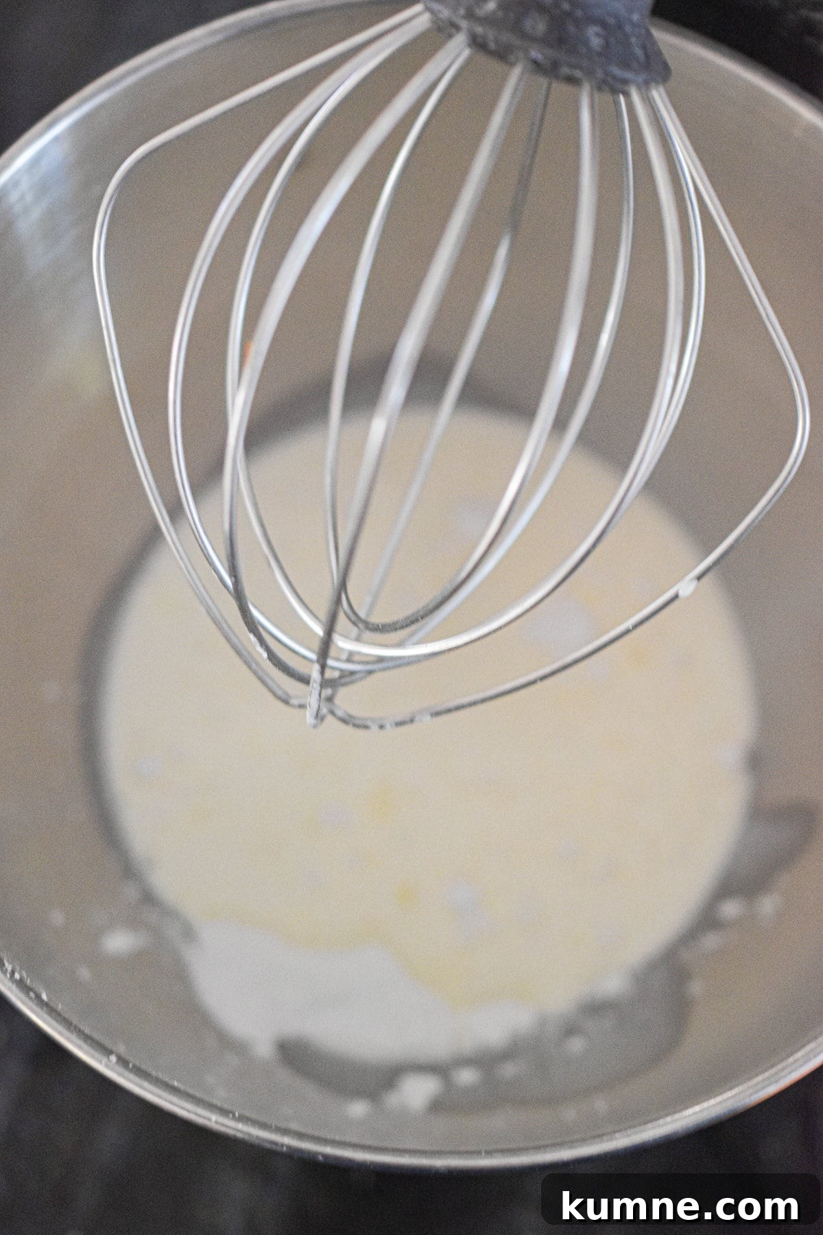 The whipped cream is in the bowl of a stand mixer.