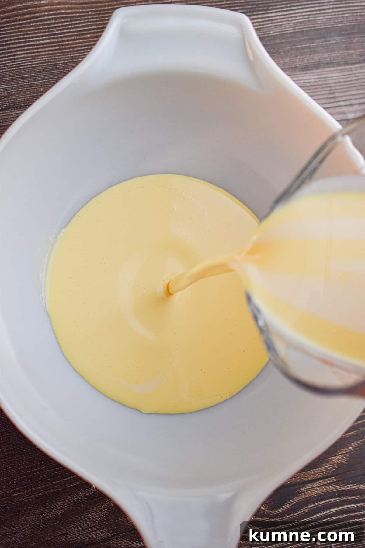 The eggnog is being poured into a large mixing bowl.