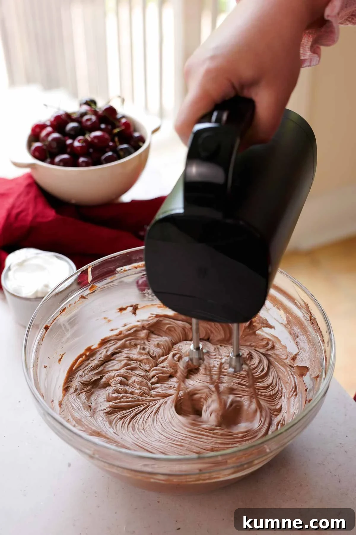 mixing cream cheese, sugar, and cocoa powder with electric mixer in large glass bowl